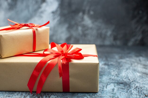 Vista frontal de regalos de navidad atados con lazos rojos en la foto de año nuevo claro-oscuro regalo de color de vacaciones navidad
