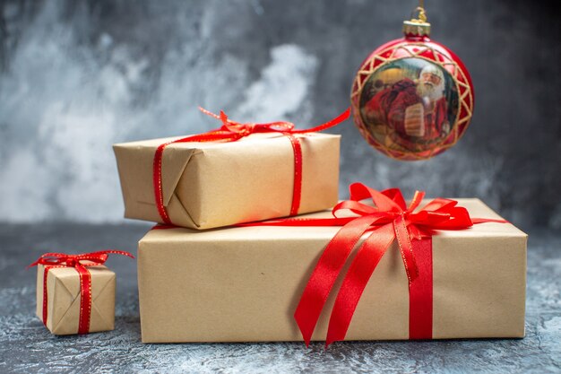 Vista frontal de regalos de navidad atados con lazos rojos en la foto de año nuevo claro-oscuro regalo de color de vacaciones navidad