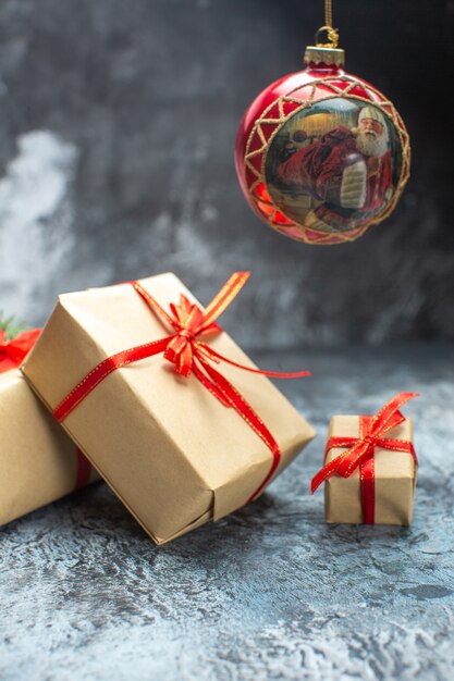 Vista frontal de regalos de navidad atados con lazos rojos en la foto de color claro-oscuro regalo de navidad de año nuevo