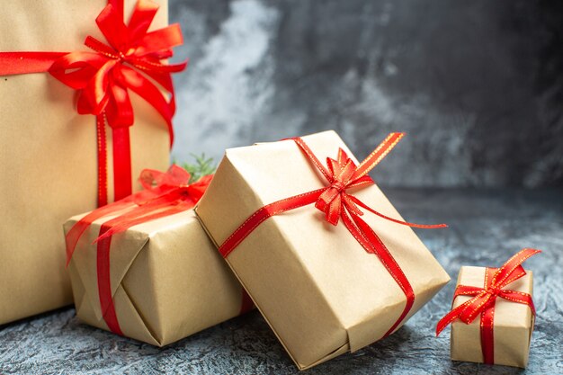 Vista frontal de regalos de navidad atados con lazos rojos en la foto en color claro-oscuro vacaciones de año nuevo regalo de navidad