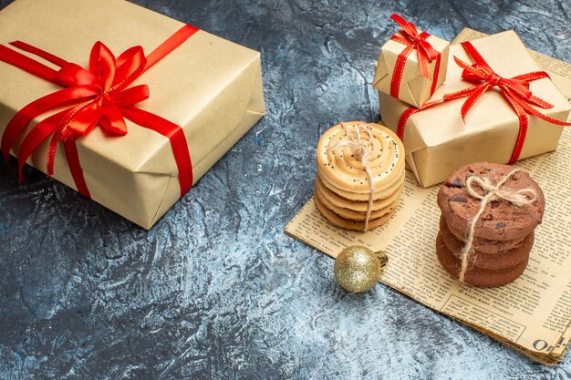 Vista frontal de regalos de navidad con galletas y juguetes en color claro-oscuro año nuevo foto de navidad regalo de vacaciones