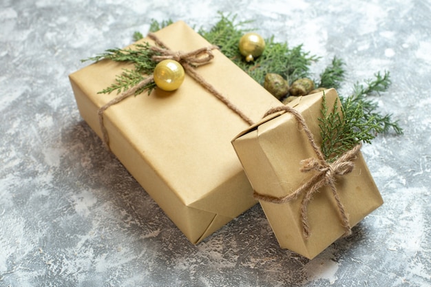 Vista frontal de regalos de Navidad con rama verde sobre fondo blanco.