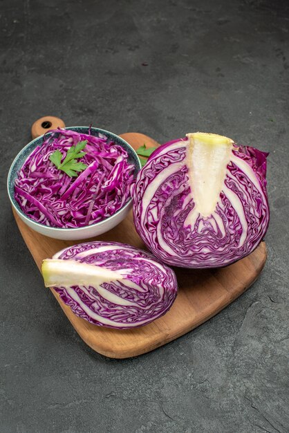 Vista frontal de repollo rojo fresco en rodajas de verduras en la mesa oscura dieta de ensalada de salud madura