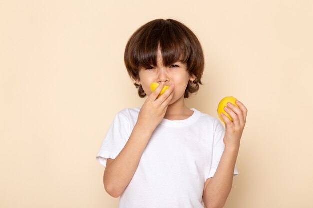 Vista frontal del retrato, niño comiendo limón en rosa