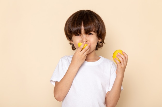 Vista frontal del retrato, niño comiendo limón en rosa