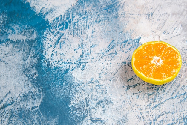 Vista frontal rodaja de mandarina fresca sobre la mesa azul claro