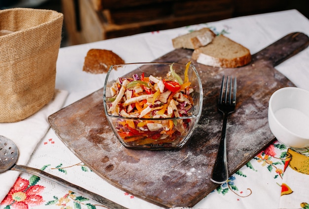 Una vista frontal en rodajas de ensalada de verduras coloridas vitaminas ricas en sal dentro de un plato transparente de color fresco en el escritorio marrón