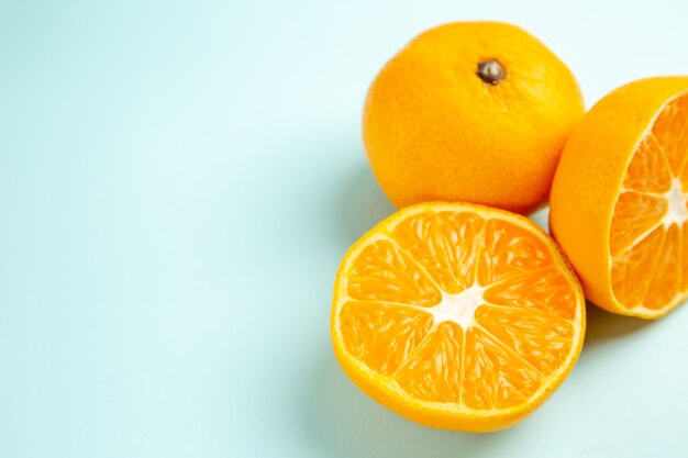 Vista frontal de rodajas de mandarina fresca sobre la mesa azul claro