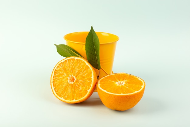 Una vista frontal en rodajas de naranja fresca madura jugosa suave aislado junto con una pequeña pieza de cesta de naranja en el blanco