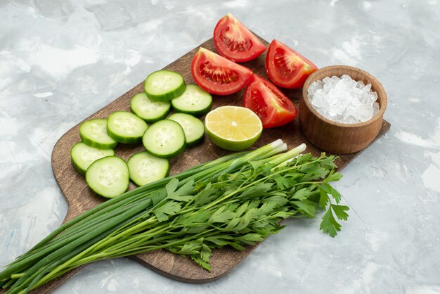 Vista frontal en rodajas de pepinos y tomates con sal verde y limón en blanco, ensalada de verduras comida verde