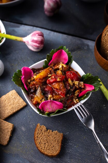 Una vista frontal rodajas de verduras carne hervida y verduras dentro del plato blanco junto con papas fritas panes en el escritorio gris comida sabrosa