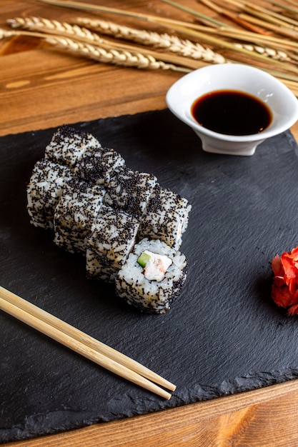 Una vista frontal rollitos de pescado rellenos de verduras en rodajas arroz junto con salsa negra harina de pescado Japón