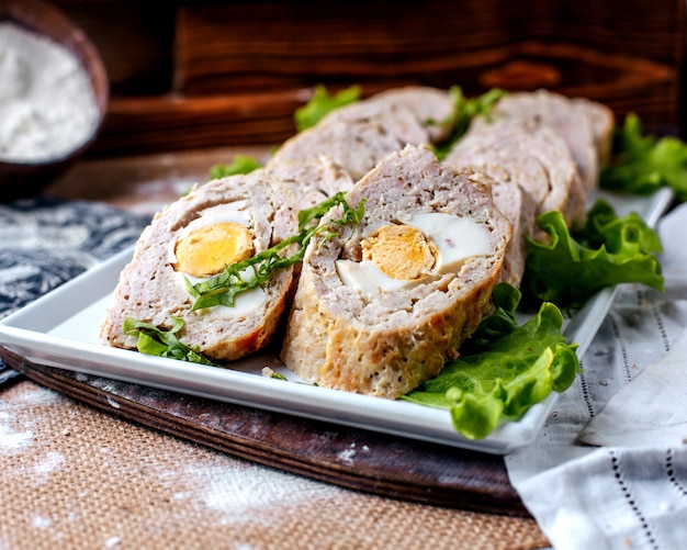 Vista frontal rollos paté sabroso sabroso con ensalada verde dentro de un plato blanco sobre la superficie marrón