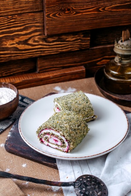 Vista frontal rollos de verduras en rodajas dentro de un plato blanco sobre la superficie marrón