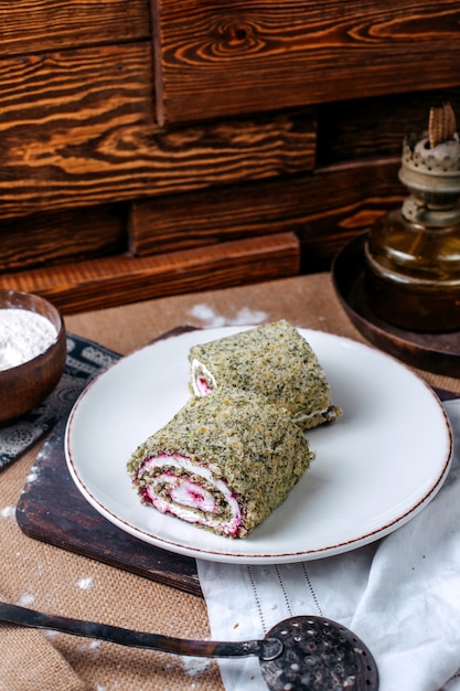 Vista frontal rollos de verduras en rodajas dentro de un plato blanco sobre la superficie marrón