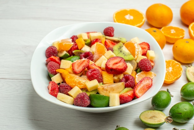 Vista frontal sabrosa ensalada de frutas con feijoas frescas y mandarinas en blanco foto madura suave árbol frutal