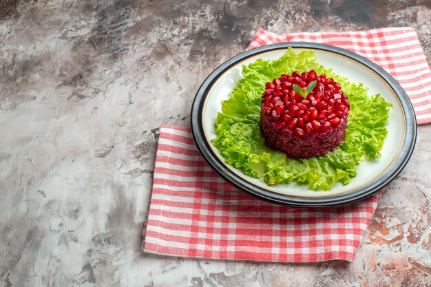 Vista frontal sabrosa ensalada de granada en forma redonda en ensalada verde en dieta de comida madura de salud de color claro