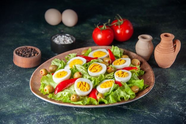 Vista frontal sabrosa ensalada de huevo se compone de aceitunas y ensalada verde sobre fondo azul oscuro