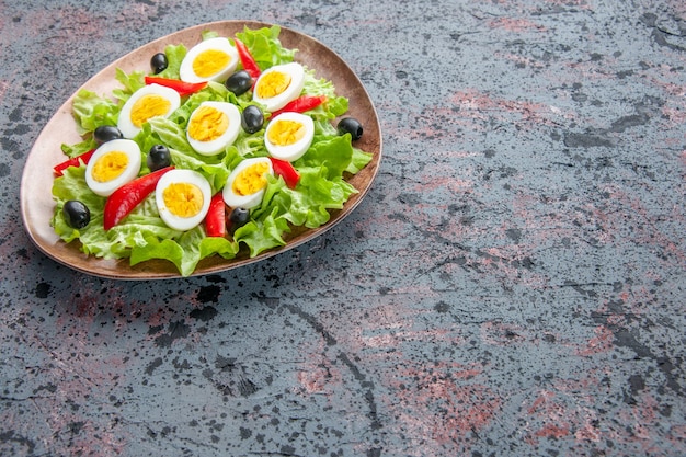 Vista frontal sabrosa ensalada de huevo con ensalada verde y aceitunas sobre fondo claro