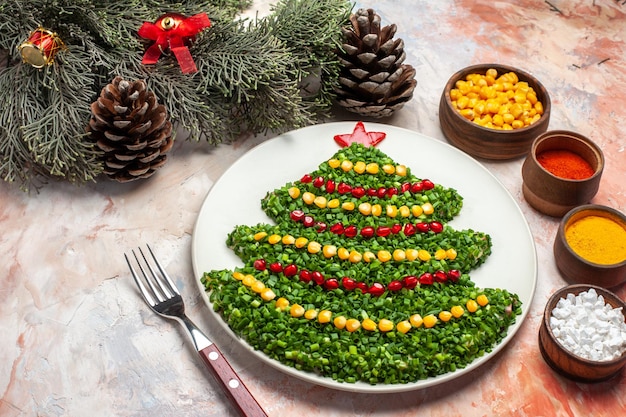 Vista frontal sabrosa ensalada verde en forma de árbol de año nuevo con condimentos sobre fondo claro