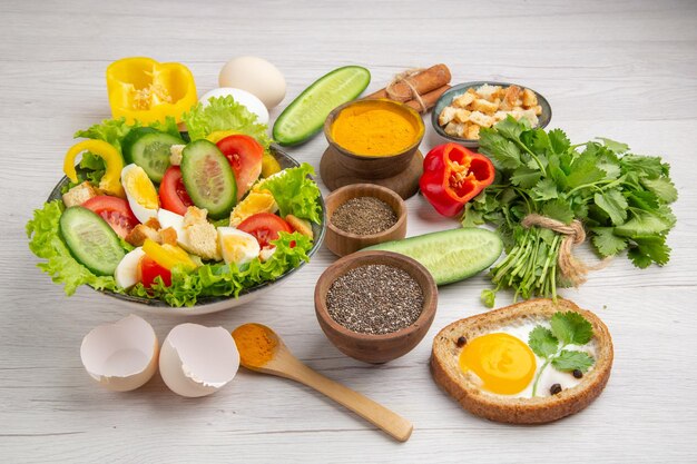 Vista frontal sabrosa ensalada de verduras con condimentos sobre fondo blanco comida comida desayuno color maduro