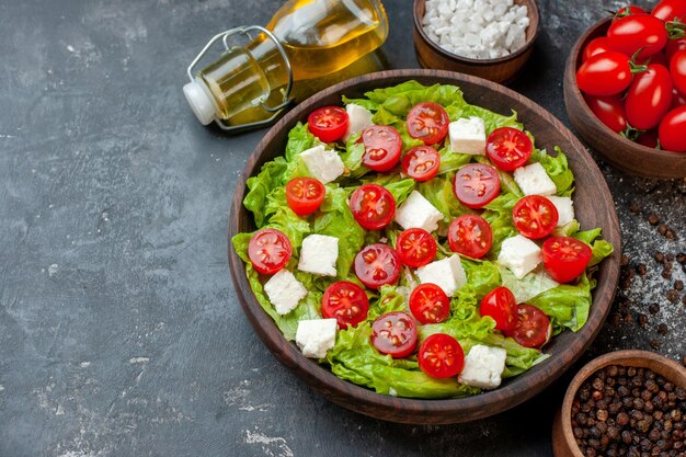 Vista frontal sabrosa ensalada de verduras con tomates con queso en rodajas y condimentos sobre fondo oscuro almuerzo dieta saludable comida comida color