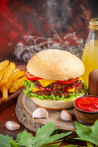 Vista frontal sabrosa hamburguesa de carne con papas fritas sobre fondo oscuro