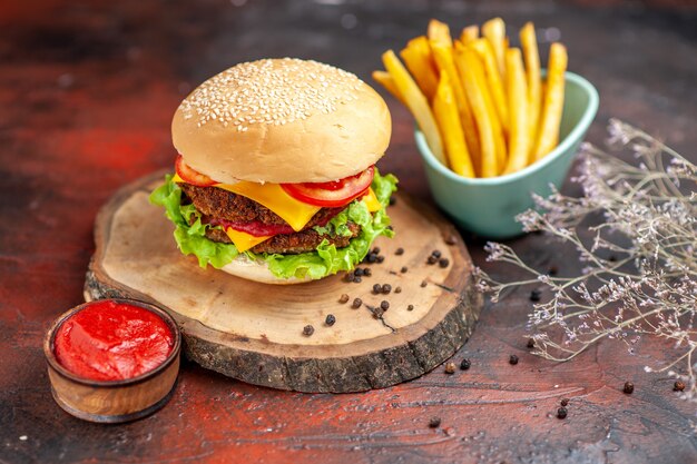 Vista frontal sabrosa hamburguesa de carne con papas fritas sobre fondo oscuro