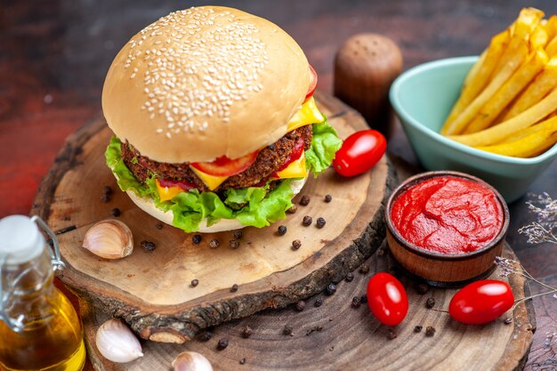 Vista frontal sabrosa hamburguesa de carne con papas fritas sobre fondo oscuro