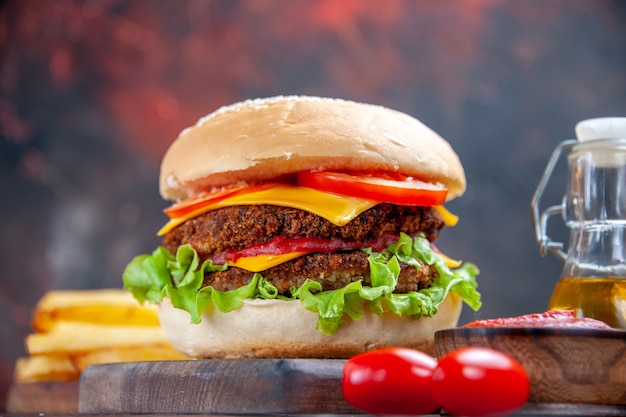 Vista frontal sabrosa hamburguesa de carne con papas fritas sobre fondo oscuro