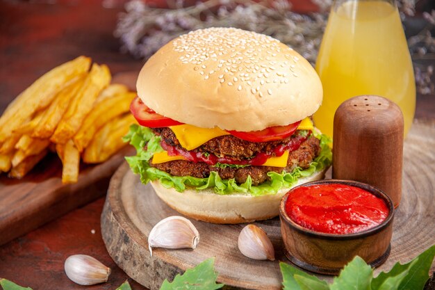 Vista frontal sabrosa hamburguesa de carne con papas fritas sobre fondo oscuro