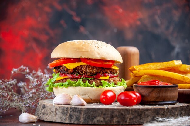 Vista frontal sabrosa hamburguesa de carne con papas fritas sobre fondo oscuro