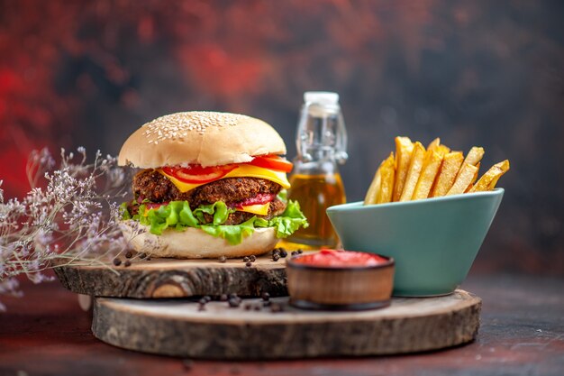 Vista frontal sabrosa hamburguesa de carne con papas fritas sobre fondo oscuro