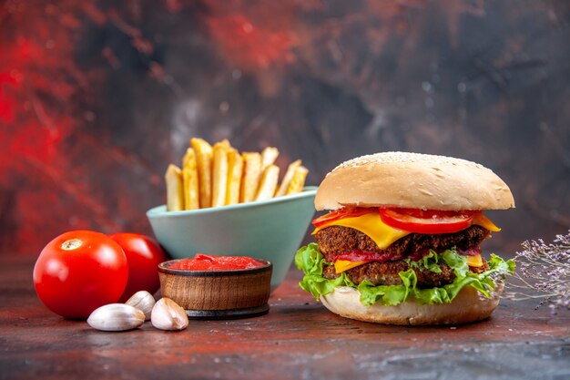 Vista frontal sabrosa hamburguesa de carne con papas fritas sobre fondo oscuro