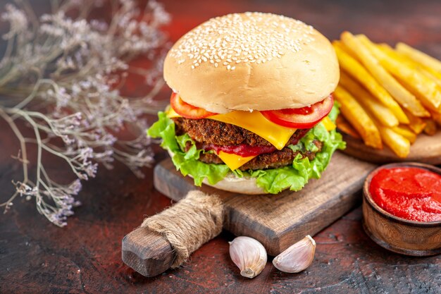 Vista frontal sabrosa hamburguesa de carne con papas fritas sobre fondo oscuro