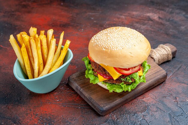 Vista frontal sabrosa hamburguesa de carne con papas fritas sobre fondo oscuro