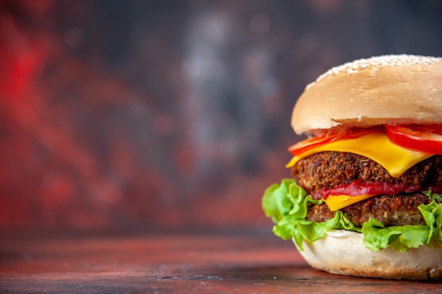 Vista frontal sabrosa hamburguesa de carne con queso y ensalada en el fondo oscuro