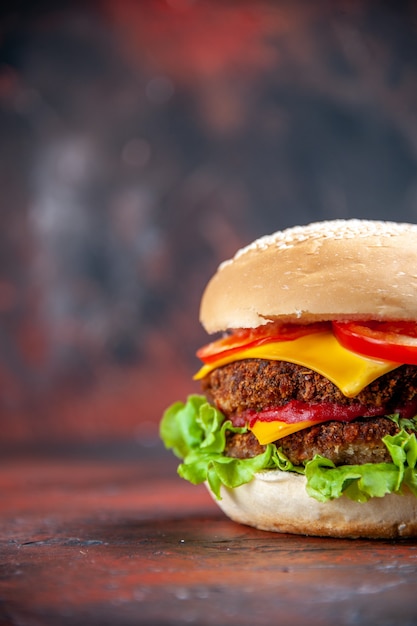 Vista frontal sabrosa hamburguesa de carne con queso y ensalada en el fondo oscuro