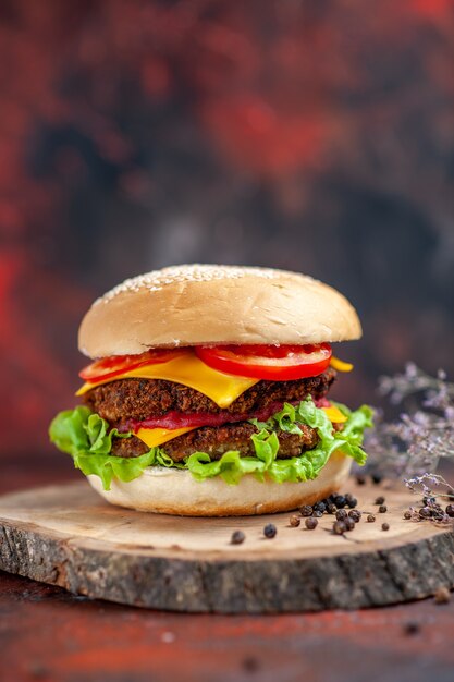 Vista frontal sabrosa hamburguesa de carne con queso y ensalada en piso oscuro