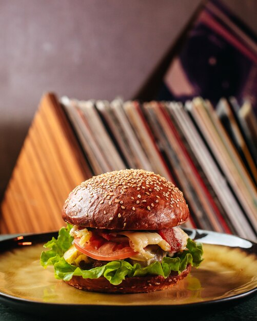 Una vista frontal sabrosa hamburguesa junto con aceitunas queso tomates y ensalada verde dentro de plato redondo