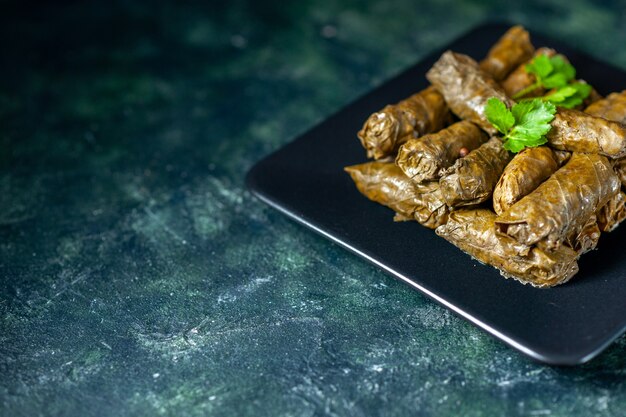 Vista frontal de la sabrosa hoja de dolma sobre fondo oscuro aceite de calorías cena comida comida ensalada plato carne