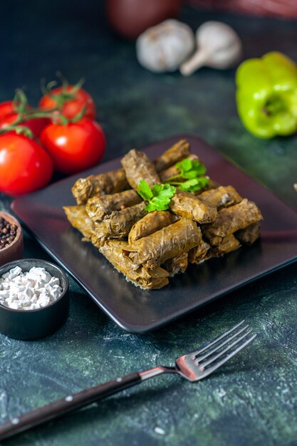 Vista frontal de la sabrosa hoja dolma con tomates en el piso oscuro aceite de calorías cena comida ensalada plato carne restaurante comida