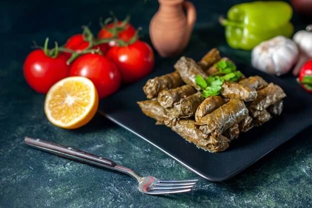 Vista frontal de la sabrosa hoja dolma con tomates sobre fondo oscuro aceite de calorías cena comida ensalada plato restaurante comida