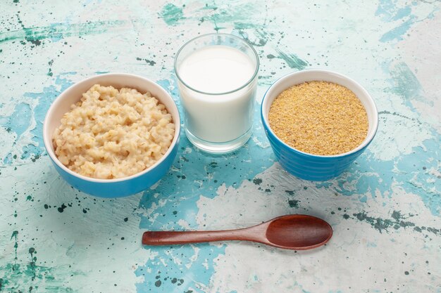 Vista frontal sabrosa papilla dentro de la placa con leche en la superficie azul desayuno leche comida comida mañana
