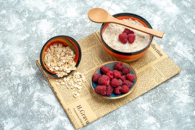 Vista frontal sabrosa papilla con frambuesas en una mesa de luz mañana foto dulce desayuno de avena