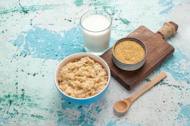 Vista frontal sabrosa papilla con leche en el escritorio azul desayuno comida comida leche