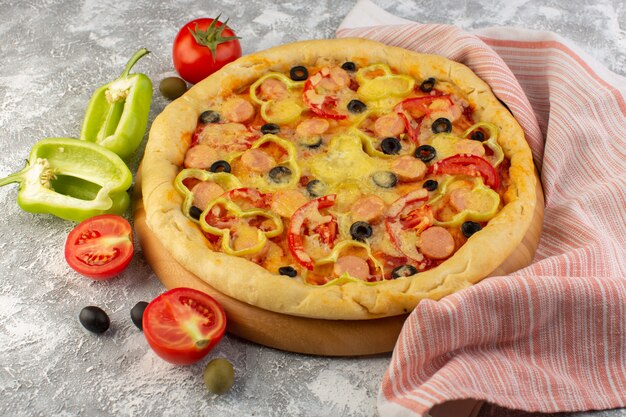 Vista frontal sabrosa pizza con queso con salchichas de aceitunas negras y tomates rojos en gris
