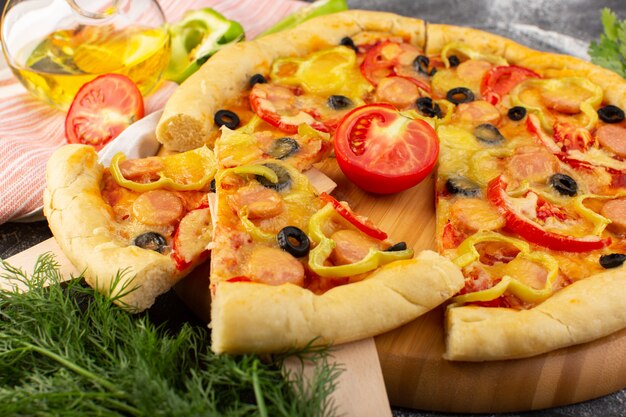 Vista frontal sabrosa pizza con queso con tomates rojos, aceitunas negras y salchichas en la oscuridad.
