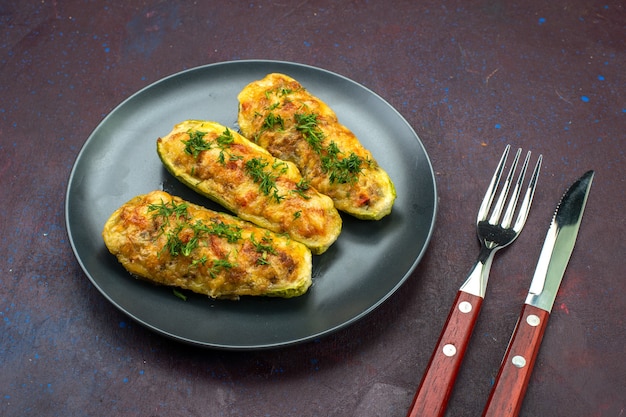 Vista frontal sabrosas calabazas al horno con verduras dentro de la placa sobre el fondo oscuro.