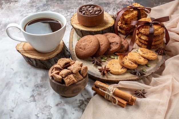 Vista frontal sabrosas galletas dulces con una taza de café en el color de fondo claro pastel de té de azúcar de cacao galleta pastel dulce